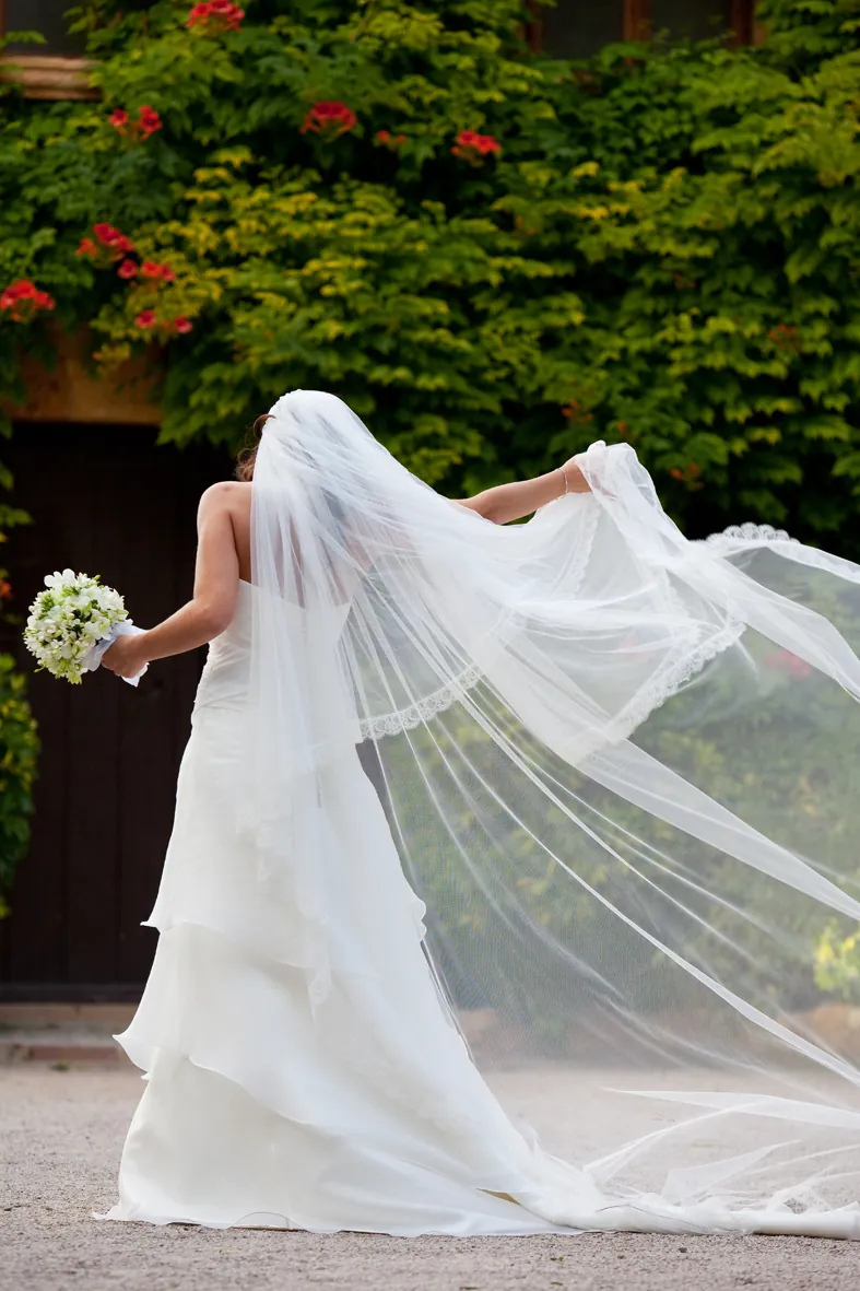 Novia caminando por un jardín con el velo al viento