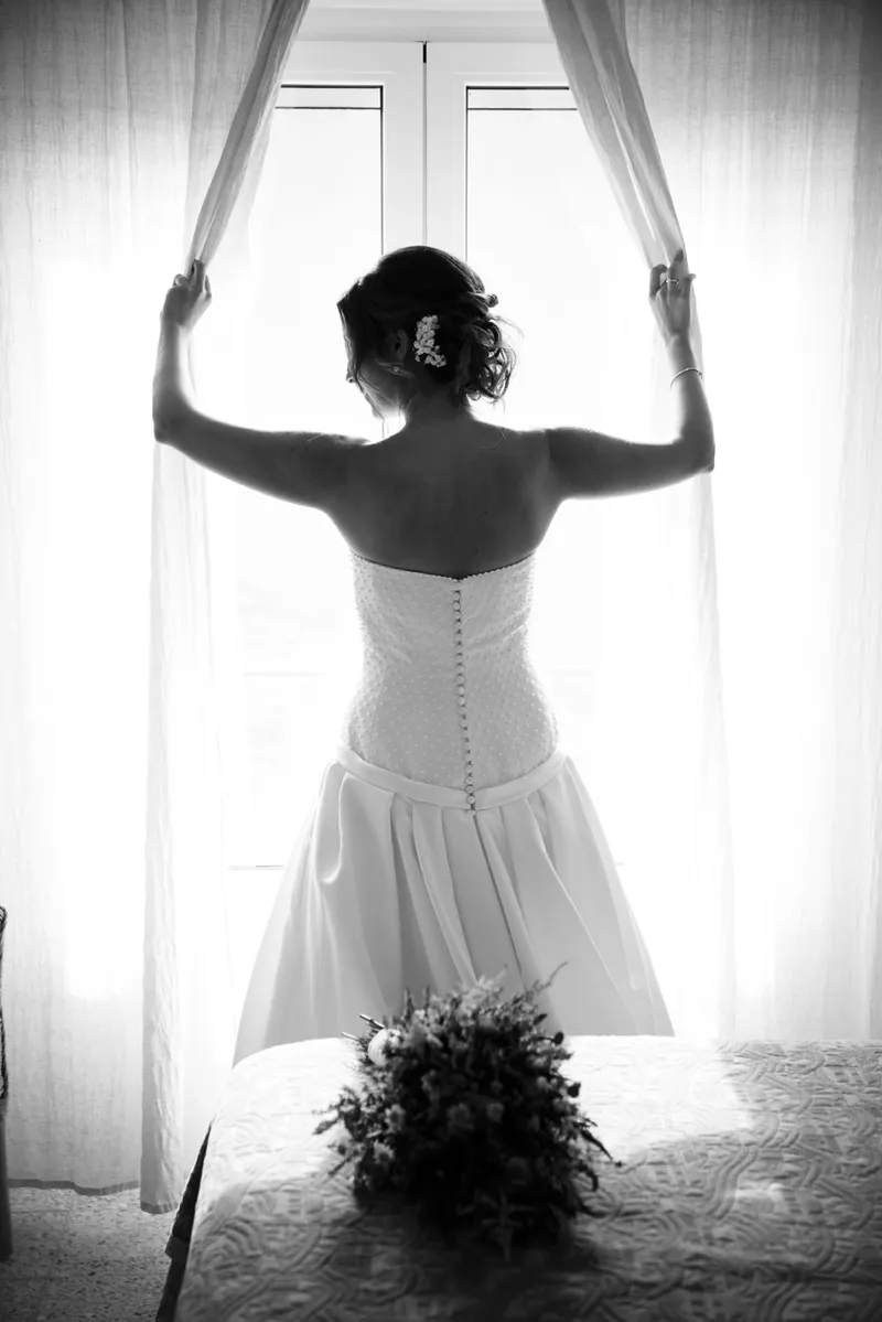 Silueta en blanco y negro de una novia abriendo las cortinas de una ventana
